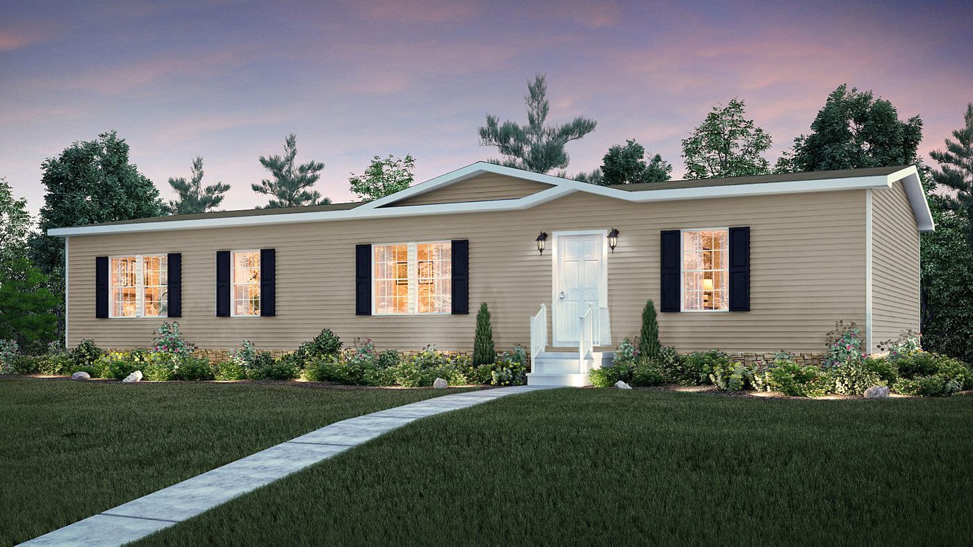 A beige manufactured home with white trim and black shutters, lit from within, sits among landscaping and grass at dusk. A straight path leads to the front door.