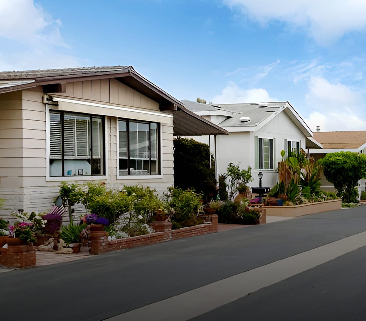 A row of cozy mobile homes with plants outside on a sunny day.