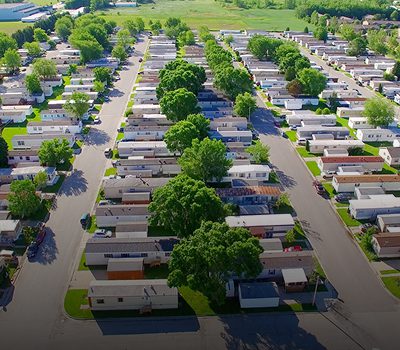 Aerial view of a large RV park with rows of parked motorhomes and green trees.
