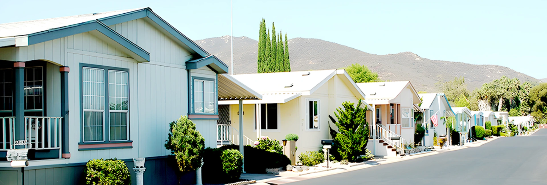 Sunny residential neighborhood with homes and trees near mountains.