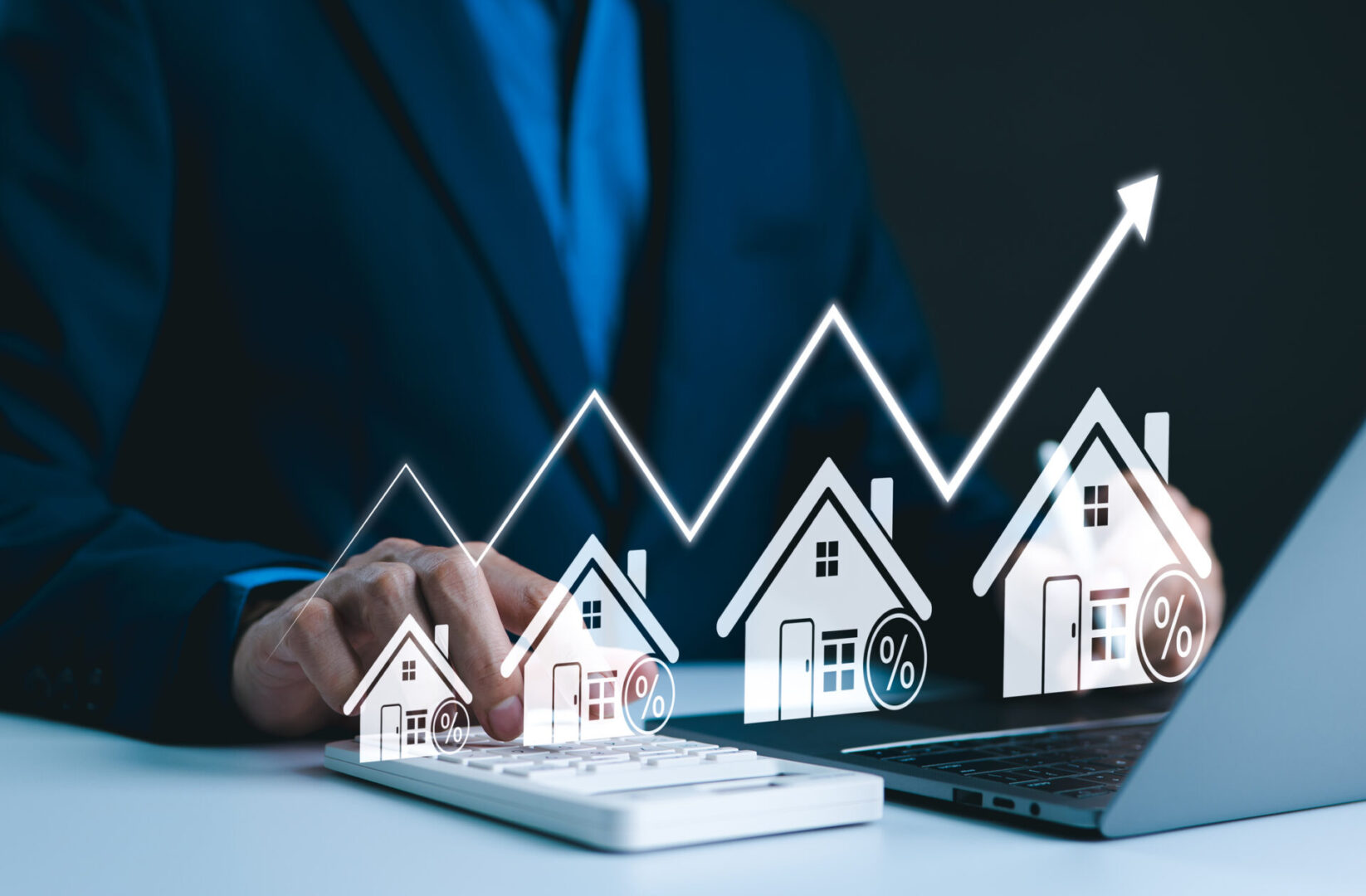 Businessman using a tablet with rising real estate market graph and house icons.