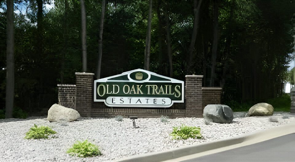 Entrance sign for Old Oak Trails Estates surrounded by greenery.