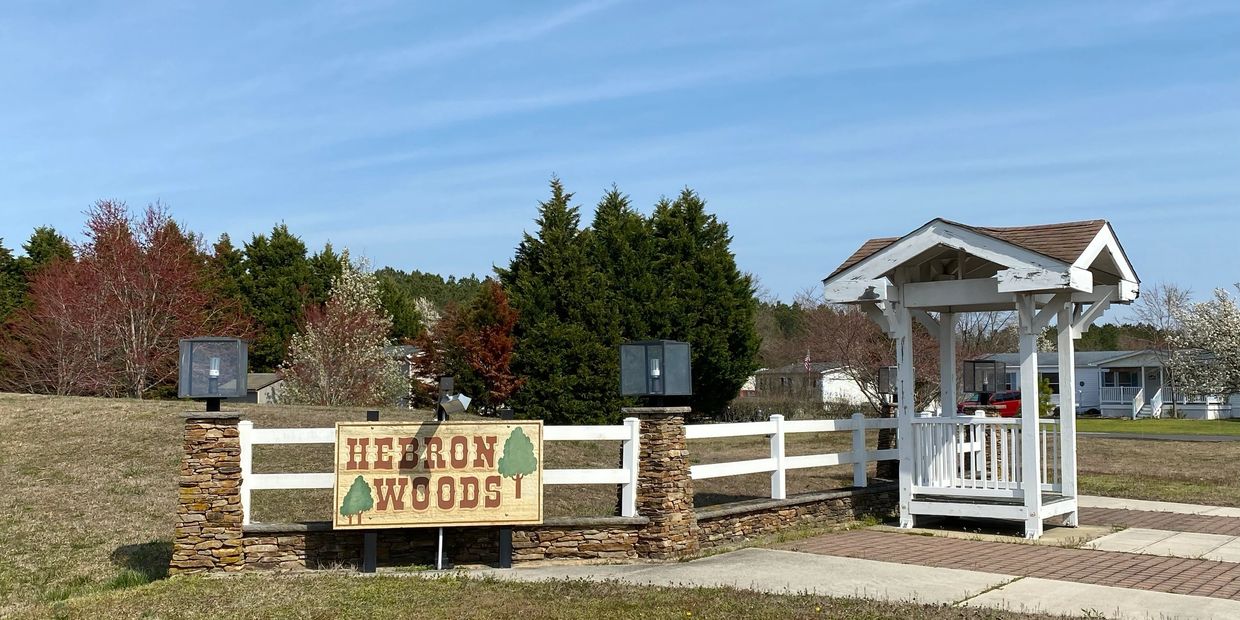 Entrance sign for Hilton Woods community with greenery and a clear sky.
