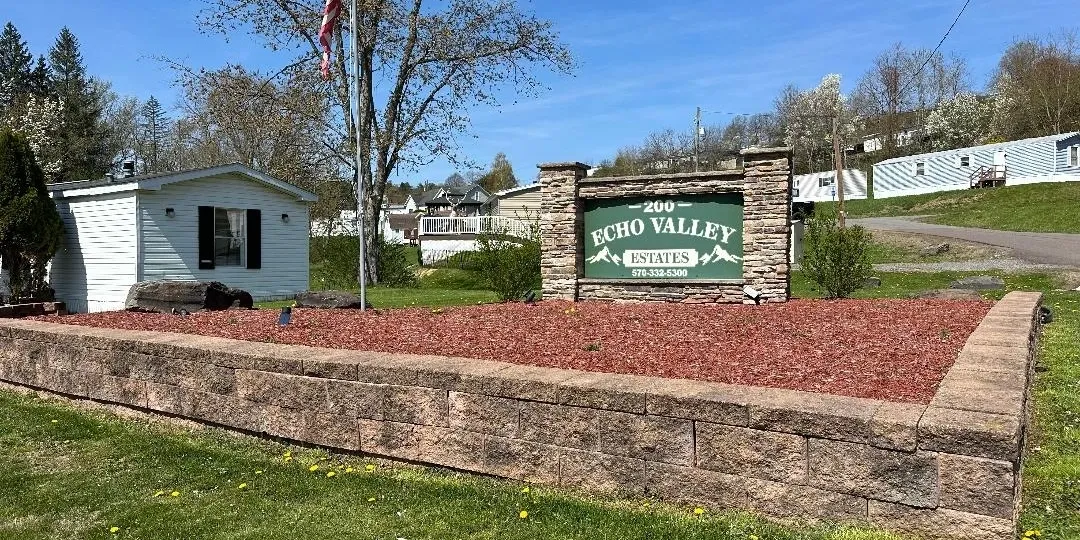 Entrance sign for Echo Valley Estates surrounded by landscaping and buildings.