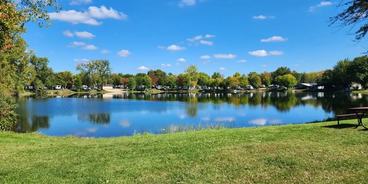 Calm lake with trees and blue sky reflecting on the water.