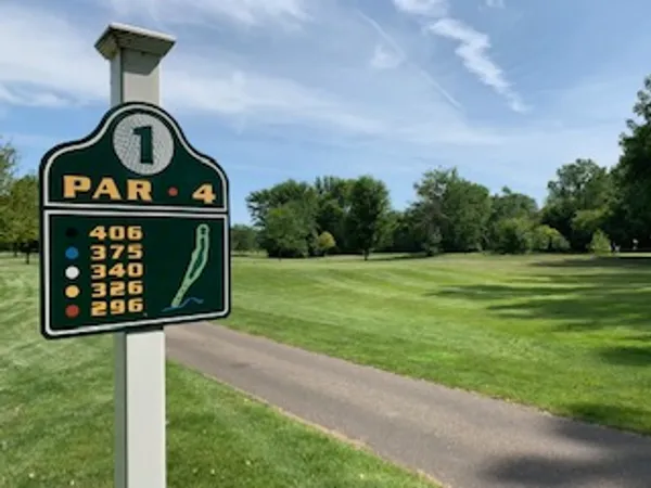 A golf course sign indicating hole 1, par 4, with yardages for different tees.