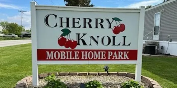 Sign for Cherry Knoll Mobile Home Park with cherry graphics.