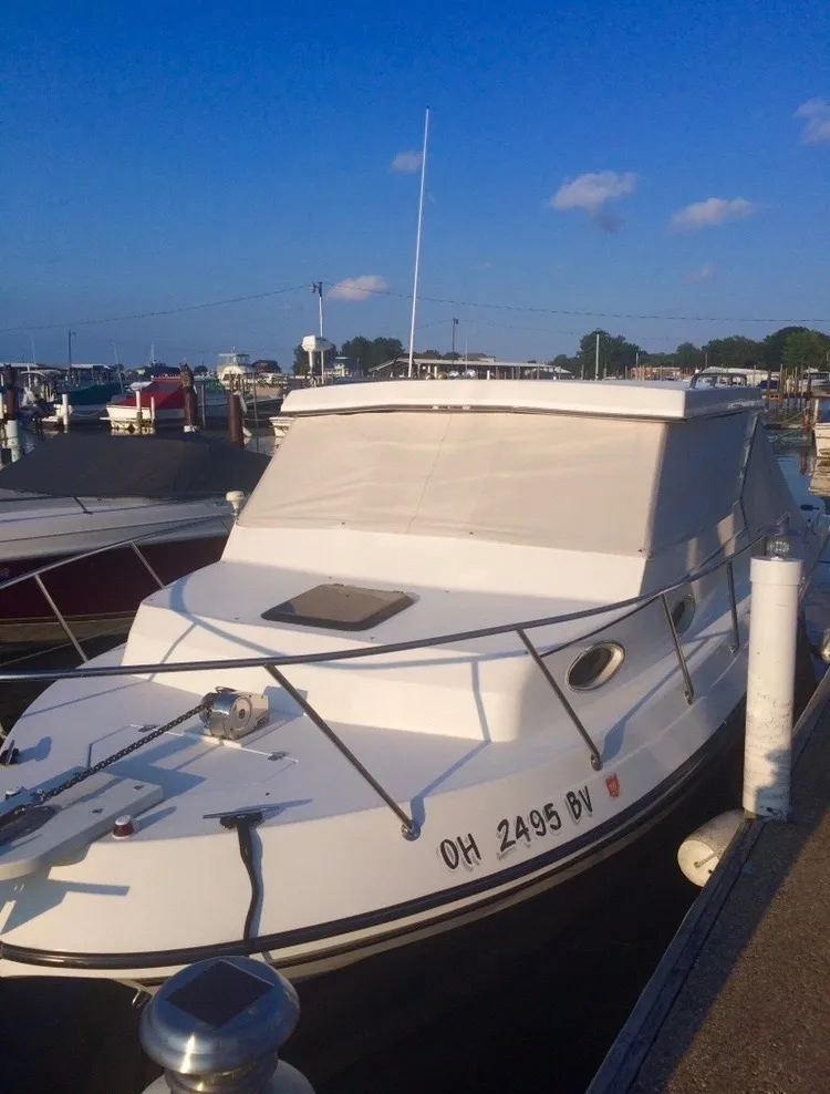 White motorboat docked in a marina on a sunny day.