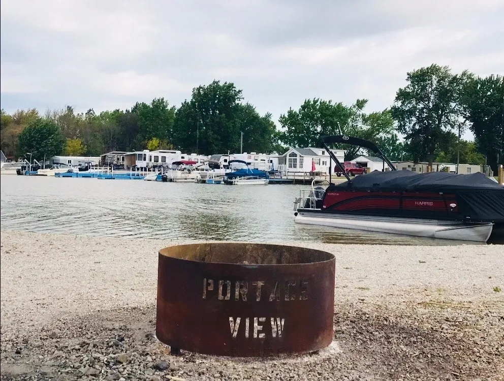 Rusty fire pit with 'Port View' text near a marina filled with boats.