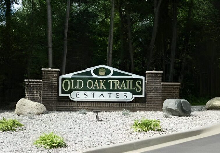 Entrance sign for Old Oak Trails Estates surrounded by greenery.