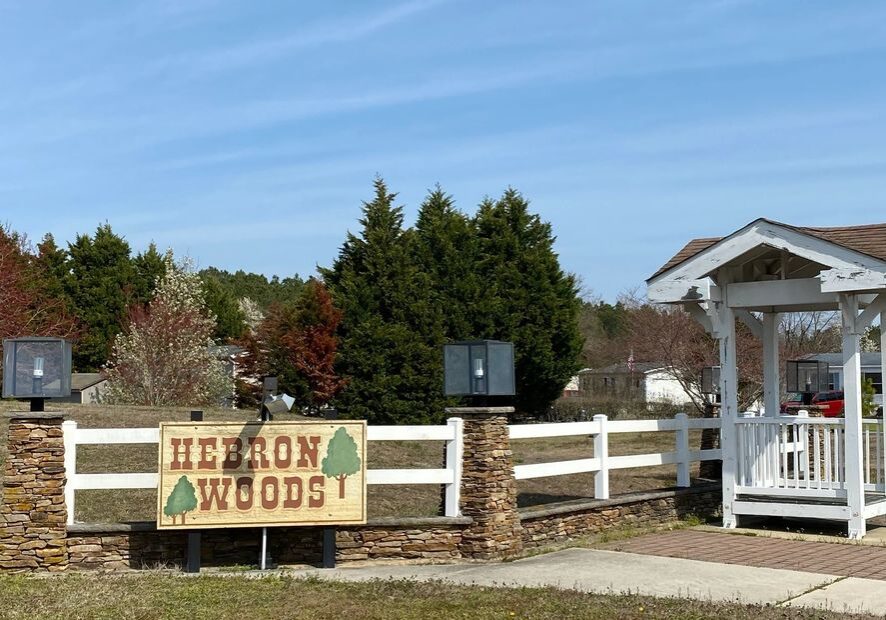Entrance sign for Hilton Woods community with greenery and a clear sky.