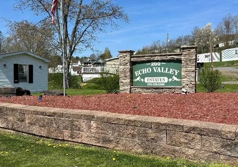 Entrance sign for Echo Valley Estates surrounded by landscaping and buildings.