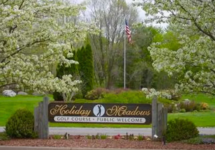 Entrance sign for Holiday Meadows residential community with blooming trees.