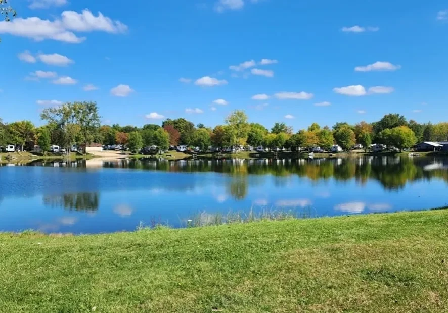 Calm lake with trees and blue sky reflecting on the water.