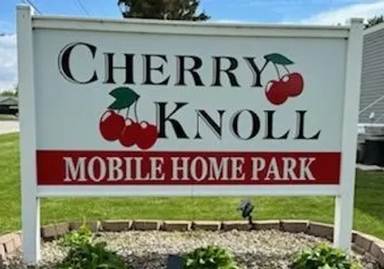 Sign for Cherry Knoll Mobile Home Park with cherry graphics.